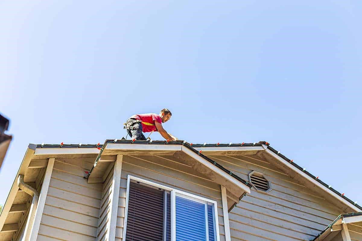 Worker installing Christmas lights on a roof in Seattle, WA