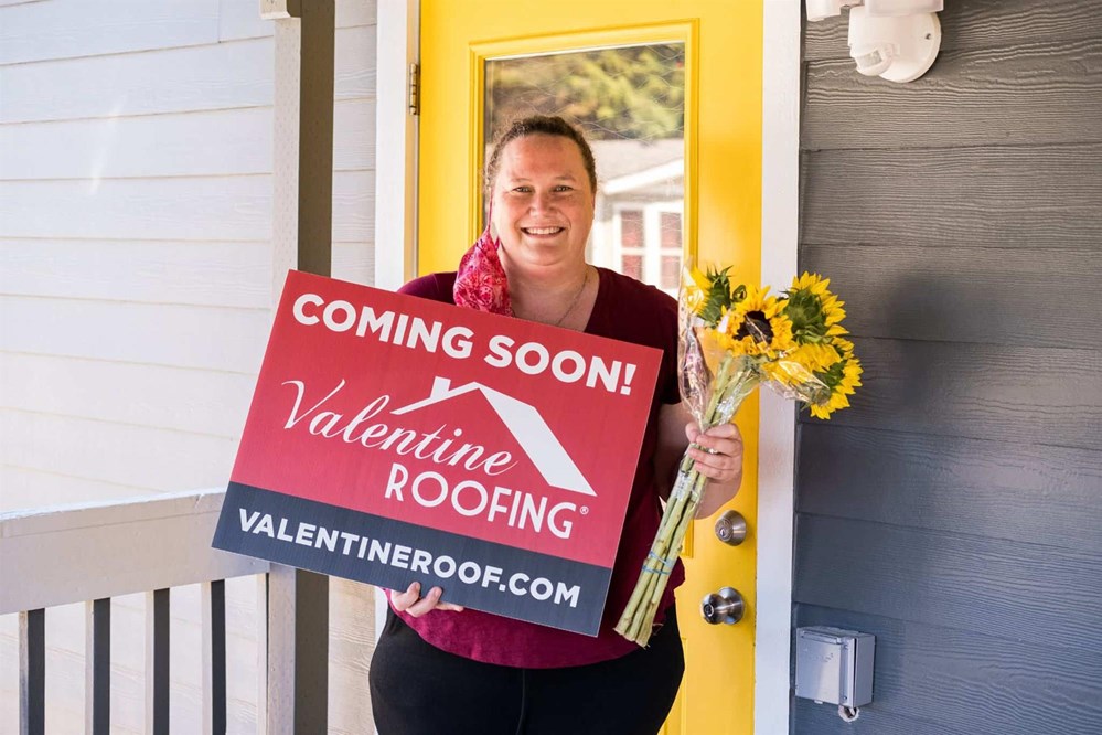 gabby holding a Valentine Roof coming soon sign 