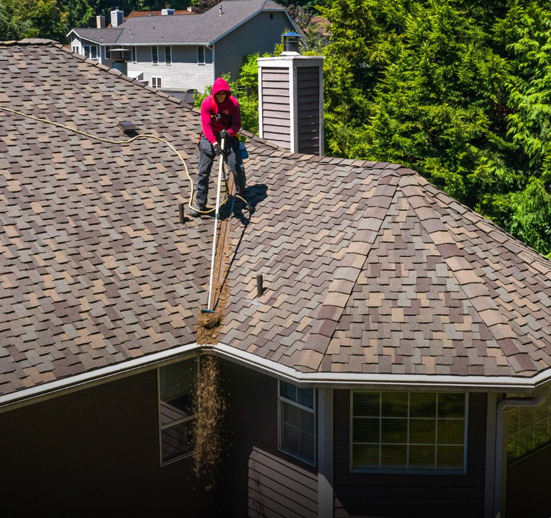 Seattle roofer cleaning debris off residential roof in Washington