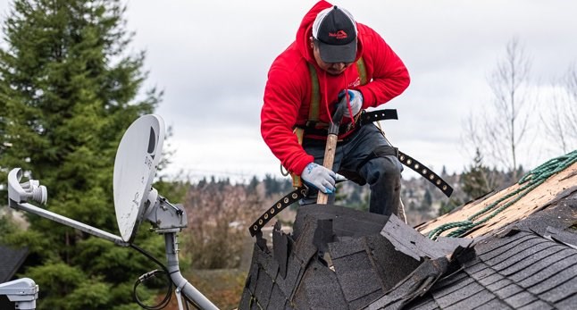Roofing contractor removing and replacing asphalt shingles on home in Seattle, Washington